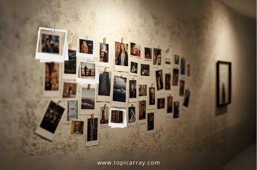 A DIY photo clip wall display featuring a large, clustered arrangement of Polaroid-style photos attached to a textured wall, offering a cheap and personalized decor solution.